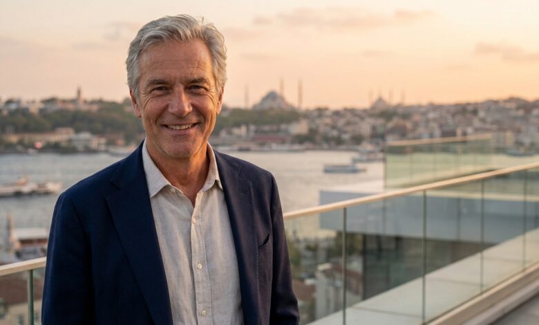 Ein glücklicher, reifer Mann mit perfekten Zähnen lächelt zufrieden auf einem Balkon, im unscharfen Hintergrund ist die Skyline von Istanbul bei Sonnenuntergang zu sehen.