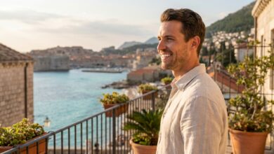 Ein glücklicher Mann mittleren Alters mit einem perfekten weißen Lächeln auf einem Hotelbalkon, im unscharfen Hintergrund die sonnige Küste der Türkei.