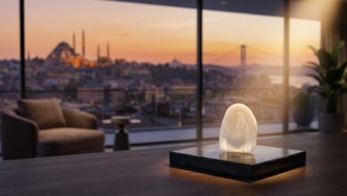 Eine einzelne, perfekte Zahnverblendschale aus Keramik im scharfen Fokus, im Hintergrund eine unscharfe, goldene Ansicht der Istanbuler Skyline bei Sonnenuntergang, die Medizintourismus darstellt.