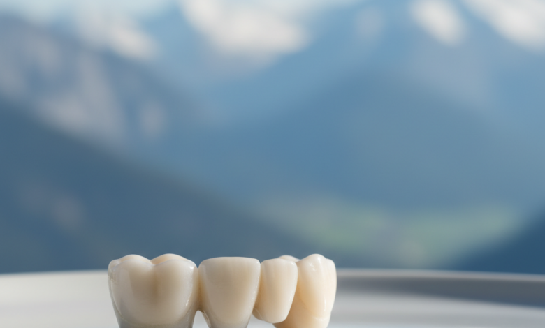A close-up, photorealistic image of a sparkling white ceramic dental bridge resting on a sterile surface. The background is a highly blurred, out-of-focus view of the majestic Swiss Alps under a bright, clear sky. The focus is sharp on the dental bridge, highlighting its intricate detail and quality.