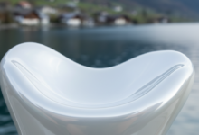 A pristine, abstract white surface, perfectly smooth and curved to suggest dental precision and aesthetic beauty, against a soft-focus background of a traditional Swiss village and a tranquil lake surrounded by mountains.