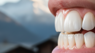 Close-up of brilliantly white, healthy human teeth with a shallow depth of field, showing a softly blurred, picturesque Swiss mountain landscape in the background.