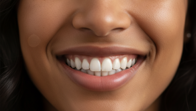 Close-up of a person smiling confidently with perfect, bright white teeth, set against a beautifully blurred background of the majestic Swiss Alps under a clear sky. The lighting is soft and natural, emphasizing the radiant smile.
