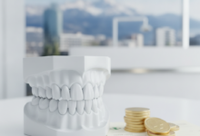 A close-up, conceptual image showing a clean dental model, a stack of golden coins, and blurred abstract insurance documents, set against a softly blurred Swiss mountain backdrop, symbolizing dental care costs and insurance in Switzerland.