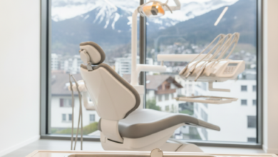 A clean, modern dental clinic room with advanced instruments on a tray in the foreground and a comfortable dental chair in the mid-ground. Through a large window, a blurred view of a Swiss city and mountains is visible in the background, conveying high-quality dental care in Switzerland.